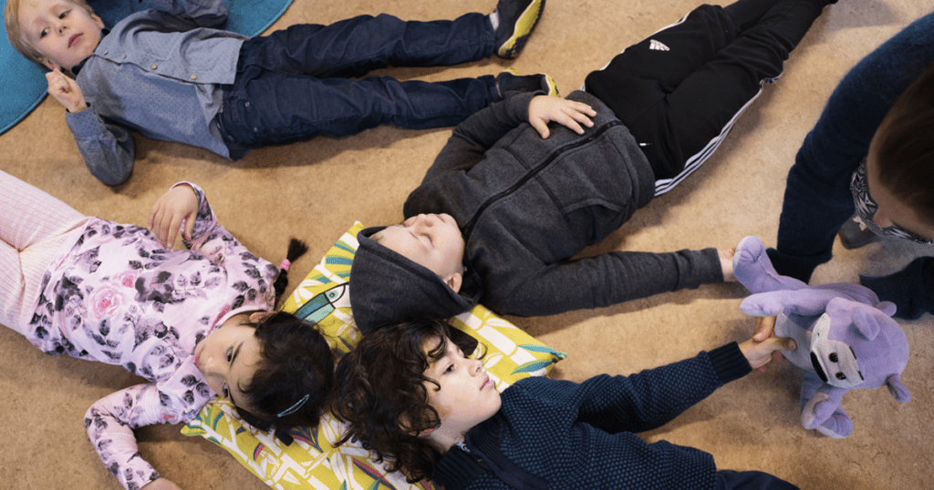 Fire skolebørn ligger på gulvet